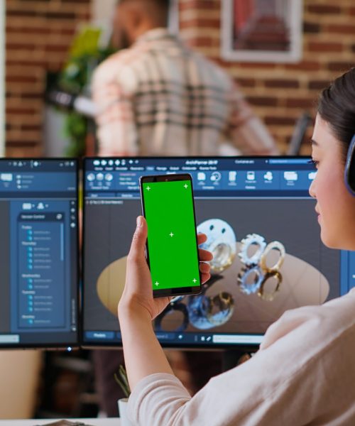 Asian freelancer developer working with headphones and chroma key screen, creating a new prototype for manufacturing industry. Female 3D modeling engineer at her home office. Camera B.